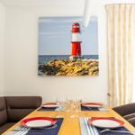 Esszimmer mit Tisch, Stühlen und Leuchtturm-Bild an der Wand.