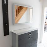 Schwarzer Schrank mit Spiegel und Holztreppe im Hintergrund