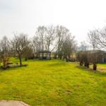 Grüner Garten mit kleinem Pavillon und Bäumen ohne Blätter.