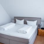 Schlafzimmer mit Doppelbett, Nachttisch und Bild an der Wand.