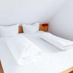 Ein Schlafzimmer mit einem Bett, zwei Kissen, einer Bettdecke und einer Nachttischlampe.