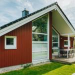 Rotes Holzhaus mit Terrasse und Sitzgelegenheiten im Garten.