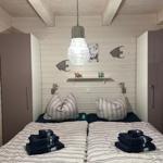 Zwei Betten mit gestreiften Bettwäsche und Handtüchern. Holzwand und Decke mit Fischdekoration.