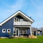 Blau gestrichenes Haus mit Balkon und Terrasse im Garten