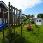 Hinterhof mit Spielplatz, Rutsche und Schaukel. Rotes Haus und graue Garage sind sichtbar.