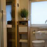 Badezimmer mit Dusche, Waschbecken und Pflanze.