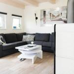 Wohnzimmer mit grauem Sofa, weißem Couchtisch und Kamin