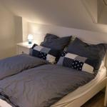 Doppelbett mit Kissen und Nachttischen unter Dachschrägen