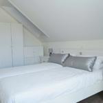 Schlafzimmer mit Dachschrägen, weißem Bett und Nachttischen.
