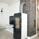 Moderne Kamineinheit neben Backsteinmauer mit Fernseher und Holzboden