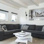 Ein Wohnzimmer mit grauem Sofa, weißem Couchtisch und Wandbild mit Steg.
