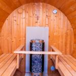 Sauna mit Holzbank und Heizung. Thermometer an der Wand.