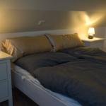 Doppelbett mit zwei Nachttischen und Lampen unter schrägem Dach