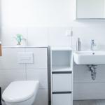 Badezimmer mit Toilette, Waschbecken und Spiegelschrank.