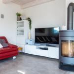 Ein Wohnzimmer mit rotem Sofa, TV und Kaminofen.