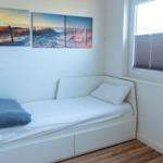 Schlafzimmer mit weißem Bett, Fenster und Wandbildern.