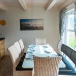 Essbereich mit Tisch, Stühlen und Fenster. Küche und Wandbild sind sichtbar.