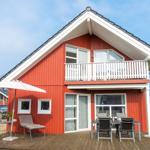 Rotes Ferienhaus mit Balkon und Terrasse mit Sitzgelegenheiten.