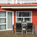 Roter Holzaufbau mit Terrasse, Tisch und Stühlen sowie Fenstern mit Vorhängen.