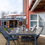 Terrasse mit Tisch, Stühlen und Sonnenschirm neben rotem Haus