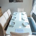 Esstisch mit sechs Stühlen und Platz für sechs Personen. Wandbild und Fenster mit Vorhang.