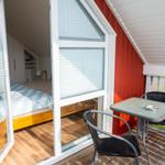 Terrasse mit Tisch und Stühlen neben Schlafzimmer mit Bett und Holzboden.