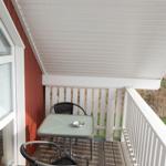 Terrasse mit Tisch und zwei Stühlen unter weißem Dach