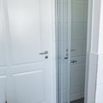 Badezimmer mit Dusche und weiße Tür.