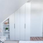 Schlafzimmer mit weißem Schrank und Holzboden. An der Wand befindet sich ein kleiner Regalschrank.