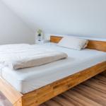 Ein Schlafzimmer mit Holzbett, weißen Nachttischen und Holzboden.