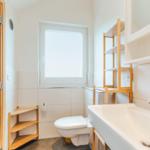 Badezimmer mit Waschbecken, Toilette und Fenster