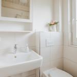 Badezimmer mit Waschbecken, Spiegel und Fenster