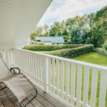 Terrasse mit Liegestuhl und Blick auf grünen Garten und Wald.