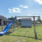 Hinterhof mit Spielplatz, Schaukel und Rutsche auf grünem Rasen.