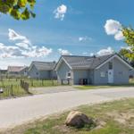 Ein modernes Ferienhaus mit Spielplatz und Garten unter blauem Himmel.