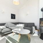 Wohnzimmer mit grauem Sofa, runder Tisch und Kaminofen.