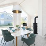 Essbereich mit Tisch, Stühlen und großen Fenstern. Schwarzer Kamin und weiße Wände.