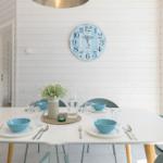 Esszimmer mit weißem Tisch, blauen Schalen und Wanduhr.