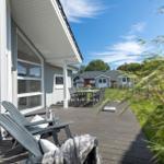 Terrasse mit Liegestühlen und Tisch, Blick auf Garten und Ferienhaus.