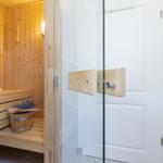 Sauna mit Holzbank und Lavendeltopf. Glaswand und Heizkörper daneben.