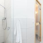 Dusche mit Duschbrause, Handtuch und Blick in Sauna.