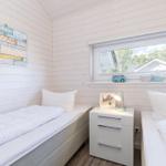 Zwei Betten mit weißen Laken, Nachttisch und Fenster mit Blick nach draußen.