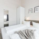 Schlafzimmer mit weißem Bett, Kleiderschrank und Wandbildern.