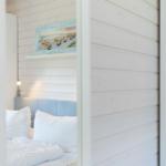 Schlafzimmer mit Bett, Wandbild und Nachttischlampe.