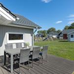 Terrasse mit Tisch und Stühlen. Grünfläche und Spielplatz im Hintergrund.