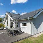 Moderne Villa mit Terrasse, Garten und Außentisch. Klare Sicht auf den Himmel.