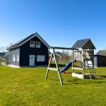 Ein Haus mit Spielplatz im Garten. Spielgeräte und grünes Gras sind sichtbar.