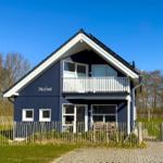 Blau gestrichenes Haus mit Balkon und Gartenzaun.