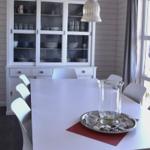 Esszimmer mit weißem Tisch, Stühlen und Schrank. Fenster und Deckenbalken sichtbar.