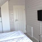 Schlafzimmer mit weißem Bett, Kleiderschrank und Wandfernseher.